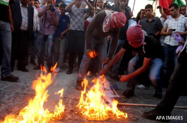 Palestinians burn Israeli flags during a support rally for Palestinian prisoners on hunger strike, in the West Bank city of Ramallah, May 6, 2012. Photo by Issam Rimawi