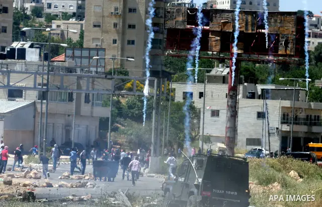 Tear gas fired by Israeli troops falls near Palestinian stone-throwers during clashes outside Ofer prison near the West Bank city of Ramallah May 7, 2012. Clashes between Israeli troops and Palestinian stone-throwers bro...