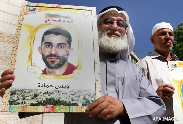 Palestinian protesters hold slogans and portraits of Palestinian prisoners, held in Israeli jails, during a demonstration in east Jerusalem on May 7, 2012 in solidarity with the prisoners. At least 1,550 imprisoned Pales...