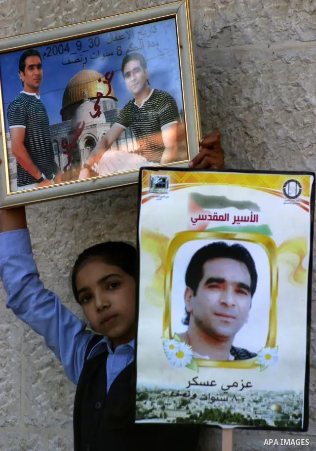 Palestinian protesters hold slogans and portraits of Palestinian prisoners, held in Israeli jails, during a demonstration in east Jerusalem on May 7, 2012 in solidarity with the prisoners. At least 1,550 imprisoned Pales...