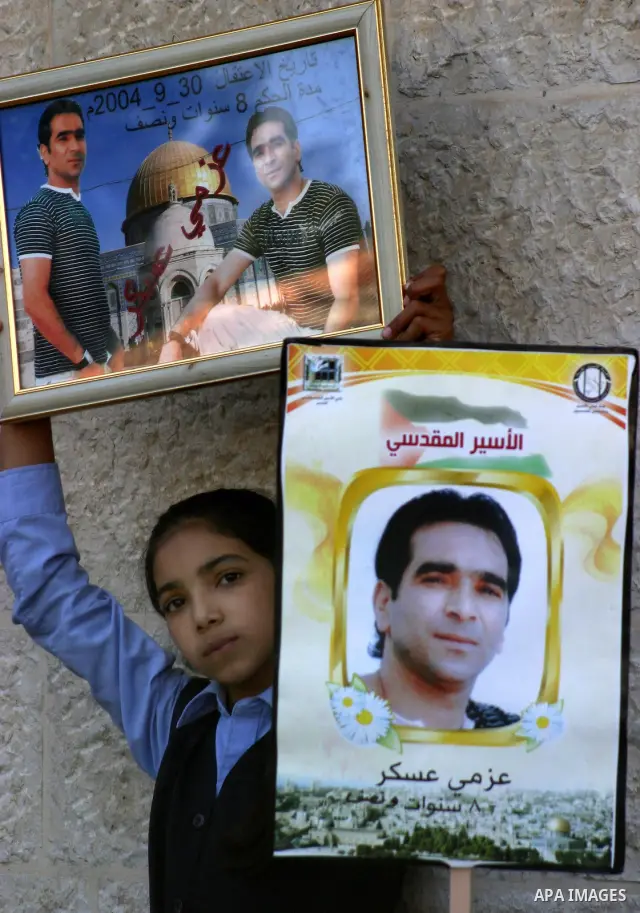 Palestinian protesters hold slogans and portraits of Palestinian prisoners, held in Israeli jails, during a demonstration in east Jerusalem on May 7, 2012 in solidarity with the prisoners. At least 1,550 imprisoned Pales...