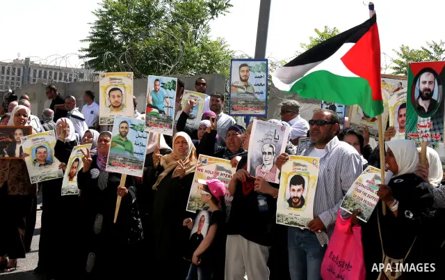 Palestinian protesters hold slogans and portraits of Palestinian prisoners, held in Israeli jails, during a demonstration in east Jerusalem on May 7, 2012 in solidarity with the prisoners. At least 1,550 imprisoned Pales...