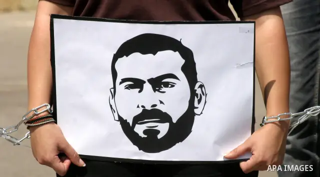 Palestinian protesters hold slogans and portraits of Palestinian prisoners, held in Israeli jails, during a demonstration in east Jerusalem on May 8, 2012 in solidarity with the prisoners. At least 1,550 imprisoned Pales...
