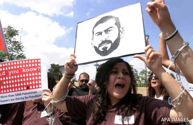 Palestinian protesters hold slogans and portraits of Palestinian prisoners, held in Israeli jails, during a demonstration in east Jerusalem on May 8, 2012 in solidarity with the prisoners. At least 1,550 imprisoned Pales...