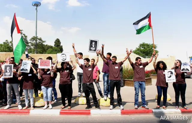 Palestinian protesters hold slogans and portraits of Palestinian prisoners, held in Israeli jails, during a demonstration in east Jerusalem on May 8, 2012 in solidarity with the prisoners. At least 1,550 imprisoned Pales...