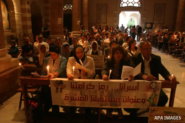 Palestinian Christians and Muslims hold pictures of incarcerated relatives during a special service at the Dominican monastery of Saint-Etienne in east Jerusalem on May 8, 2012 in solidarity with prisoners on hunger stri...
