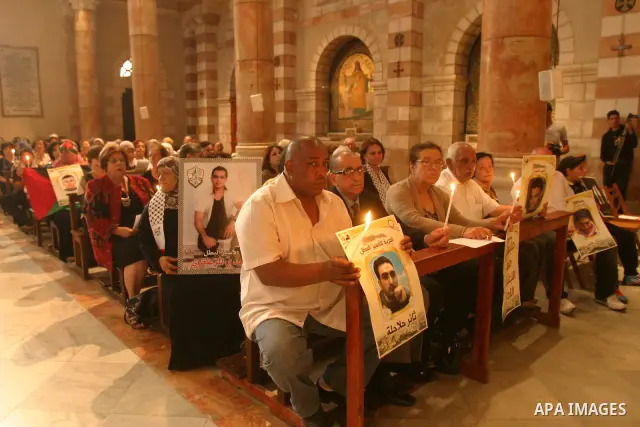 Palestinian Christians and Muslims hold pictures of incarcerated relatives during a special service at the Dominican monastery of Saint-Etienne in east Jerusalem on May 8, 2012 in solidarity with prisoners on hunger stri...