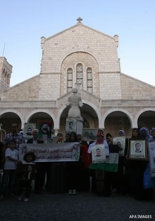 Palestinian Christians and Muslims hold pictures of incarcerated relatives during a special service at the Dominican monastery of Saint-Etienne in east Jerusalem on May 8, 2012 in solidarity with prisoners on hunger stri...