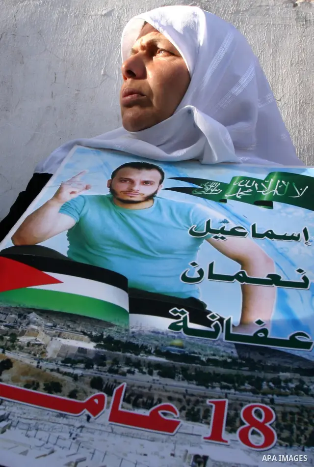 Palestinian woman holds up portrait of Palestinian prisoner, held in Israeli jails, during a demonstration in front of the Red Cross center, east Jerusalem, on May 9, 2012 in solidarity with the prisoners. At least 1,550...