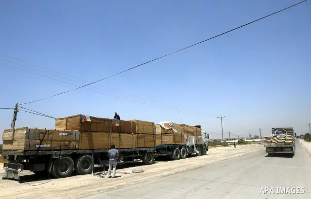 Palestinian men stand near trucks loaded with cement and building materials coming from Karem Salem crossing to Rafah in the southern Gaza Strip on 10 May 2012. Israel allowed access 250 trucks loaded with aid, for secto...