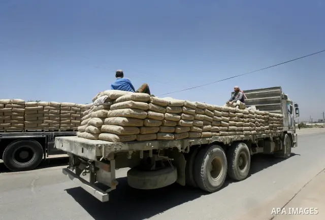 Palestinian men sit on trucks loaded with cement and building materials coming from Karem Salem crossing to Rafah in the southern Gaza Strip on 10 May 2012. Israel allowed access 250 trucks loaded with aid, for sectors o...
