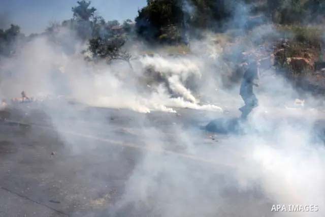 Palestinian protesters run for cover from the teargas fired by Israeli soldiers during clashes outside the Ofer Prison close to the West Bank city of Ramallah, following a demonstration in support of Palestinian prisoner...
