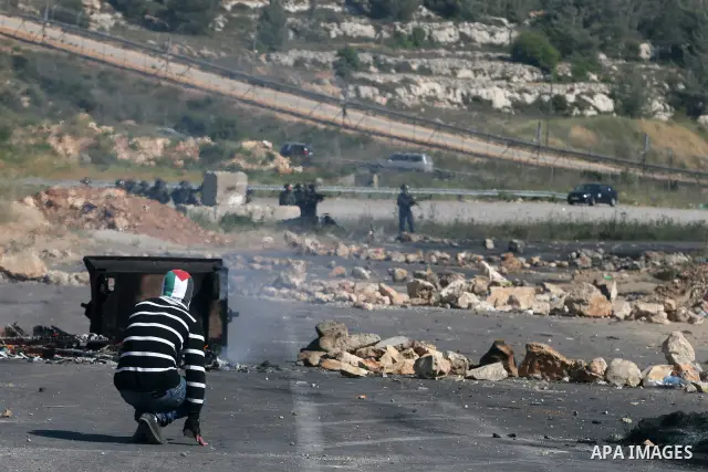 A Palestinian protester hides for cover from the teargas and rubber bullets fired by Israeli soldiers during clashes outside the Ofer Prison close to the West Bank city of Ramallah, following a demonstration in support o...