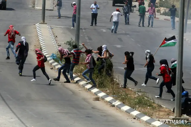Palestinian protesters run for cover from the teargas fired by Israeli soldiers during clashes outside the Ofer Prison close to the West Bank city of Ramallah, following a demonstration in support of Palestinian prisoner...