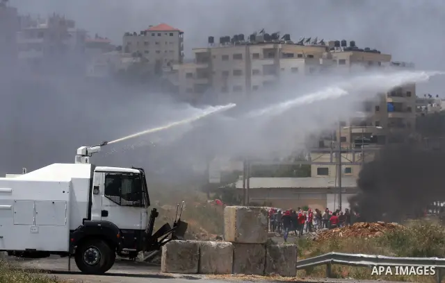 Palestinian protesters run for cover from the teargas fired by Israeli soldiers during clashes outside the Ofer Prison close to the West Bank city of Ramallah, following a demonstration in support of Palestinian prisoner...