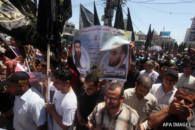 Palestinians hold up portraits of Palestinian prisoners, held in Israeli jails, and shout slogans during a demonstration in southern Gaza strip, city of Khan Younis, on May 11, 2012 in solidarity with the prisoners. At l...