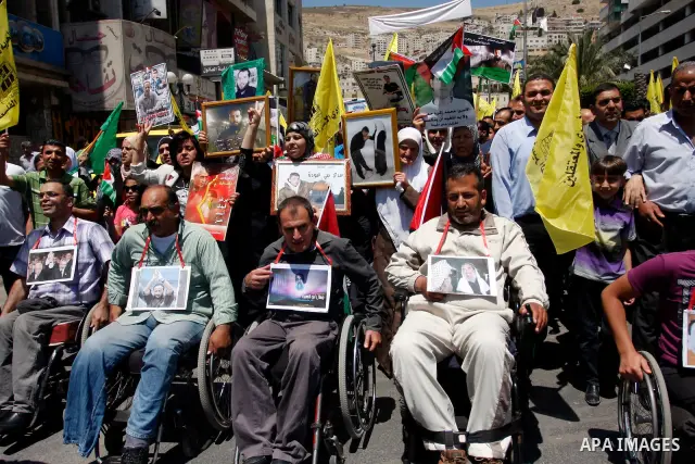 Palestinians participate a demonstration, and hold portraits of prisoners held in Israeli jails, following perform Friday prayers during a sit-in, in the West Bank city of Nablus, May 11, 2012. Palestinians held in praye...