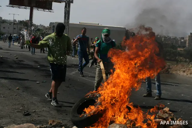 Palestinian protesters cover behind the burning tyres during clashes with Israeli soldiers outside the Ofer Prison near the West Bank city of Ramallah on May 11, 2012 following a demonstration in support of Palestinian p...