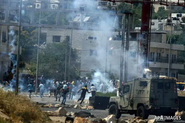 Palestinian protesters run for cover from the teargas fired by Israeli soldiers during clashes outside the Ofer Prison near the West Bank city of Ramallah on May 11, 2012 following a demonstration in support of Palestini...