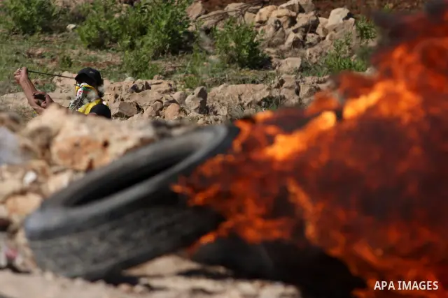 Palestinian protesters cover behind the burning tyres during clashes with Israeli soldiers outside the Ofer Prison near the West Bank city of Ramallah on May 11, 2012 following a demonstration in support of Palestinian p...