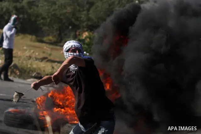 Palestinian protesters cover behind the burning tyres during clashes with Israeli soldiers outside the Ofer Prison near the West Bank city of Ramallah on May 11, 2012 following a demonstration in support of Palestinian p...