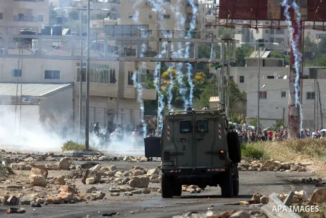 Palestinian protesters run for cover from the teargas fired by Israeli soldiers during clashes outside the Ofer Prison near the West Bank city of Ramallah on May 11, 2012 following a demonstration in support of Palestini...