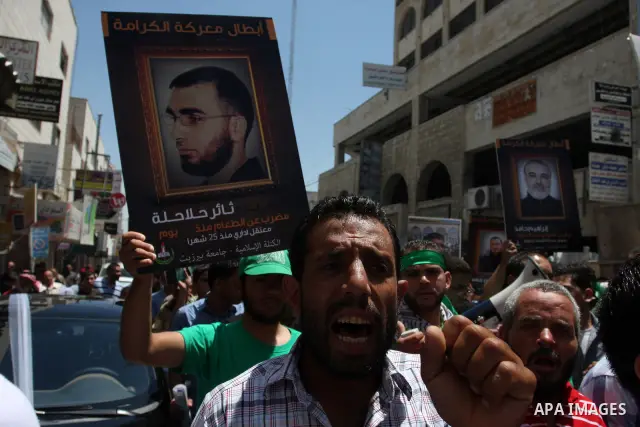 Palestinian protesters holding pictures of jailed Palestinians in Israel in the West Bank city of Ramallah, 11 May 2012, during a solidarity Rally with Palestinian prisoners in Israeli jails. The prisoners launched an op...