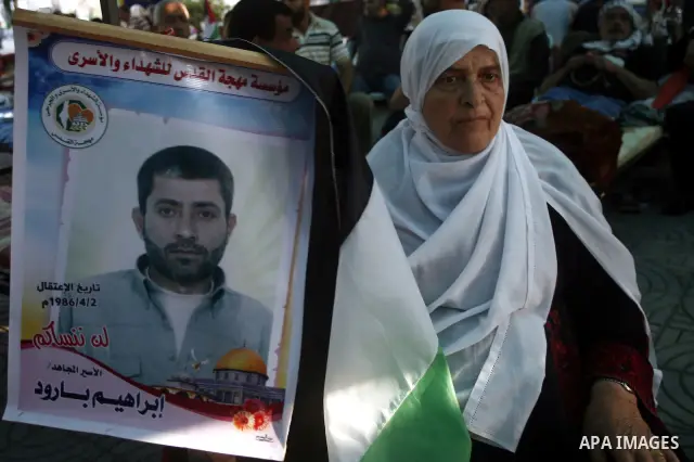 A Palestinian woman holds a framed portrait of her son, who is a prisoner in an Israeli jail, during a rally to show solidarity with prisoners held in Israeli jails, in Gaza City May 11, 2012. A hunger strike by Palestin...
