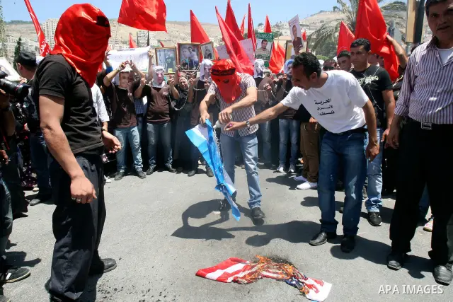 Palestinian protesters cover their faces burn Israeli and American flag during protests in the center of Nablus City , 12 May 2012 for the release of prisoners held in Israeli jails. Hundreds of Palestinians serving admi...