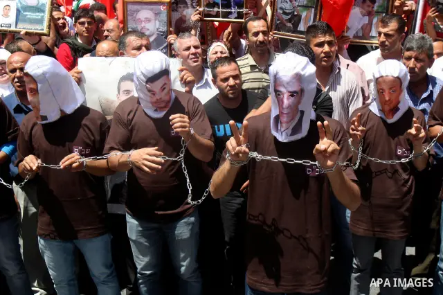 Palestinian protesters cover their faces with pictures of Palestinian prisoners during protests in the center of Nablus City , 12 May 2012 for the release of prisoners held in Israeli jails. Hundreds of Palestinians serv...