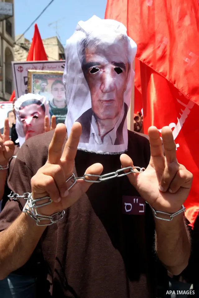 Palestinian protesters cover their faces with pictures of Palestinian prisoners during protests in the center of Nablus City , 12 May 2012 for the release of prisoners held in Israeli jails. Hundreds of Palestinians serv...