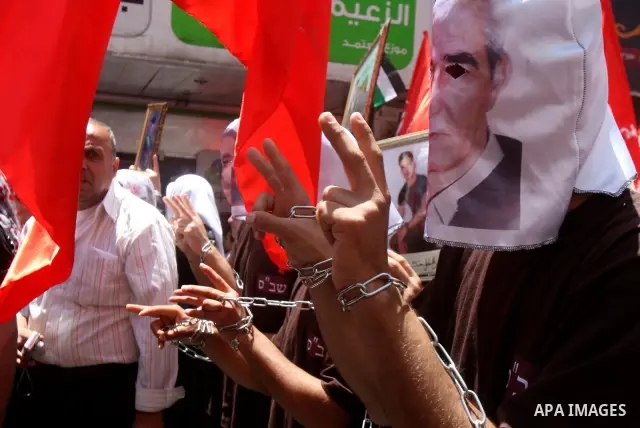 Palestinian protesters cover their faces with pictures of Palestinian prisoners during protests in the center of Nablus City , 12 May 2012 for the release of prisoners held in Israeli jails. Hundreds of Palestinians serv...
