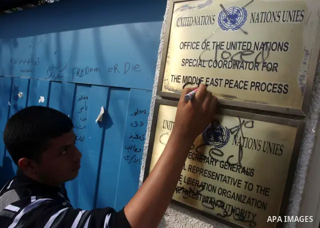 A Palestinian youth writes on the plaque of the Office of the United Nations Special Coordinator (UNSCO) headquarters in Gaza, as they forced the offices to close for two hours in solidarity with over 1,550 prisoners obs...