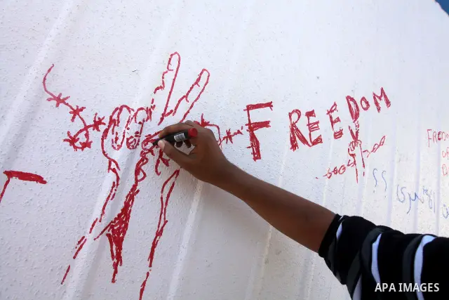 A Palestinian writes outside the headquarters of the International Committee of the Red Cross (ICRC) in Gaza as protestors forced the offices to close for two hours in solidarity with over 1,550 prisoners observing a hun...