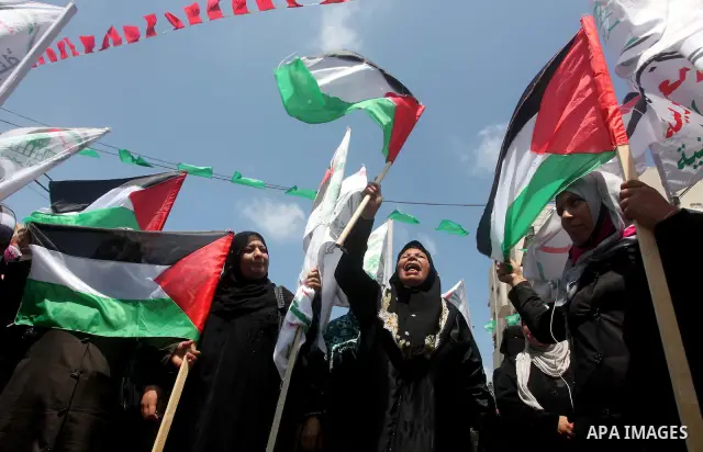 Palestinian protesters hold up signs outside the headquarters of the International Committee of the Red Cross (ICRC) during a protest in Gaza City, to show solidarity with Palestinian prisoners held in Israeli jails, May...
