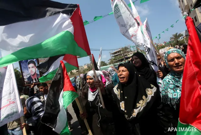 Palestinian protesters hold up signs outside the headquarters of the International Committee of the Red Cross (ICRC) during a protest in Gaza City, to show solidarity with Palestinian prisoners held in Israeli jails, May...