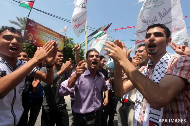 Palestinian protesters hold up signs outside the headquarters of the International Committee of the Red Cross (ICRC) during a protest in Gaza City, to show solidarity with Palestinian prisoners held in Israeli jails, May...