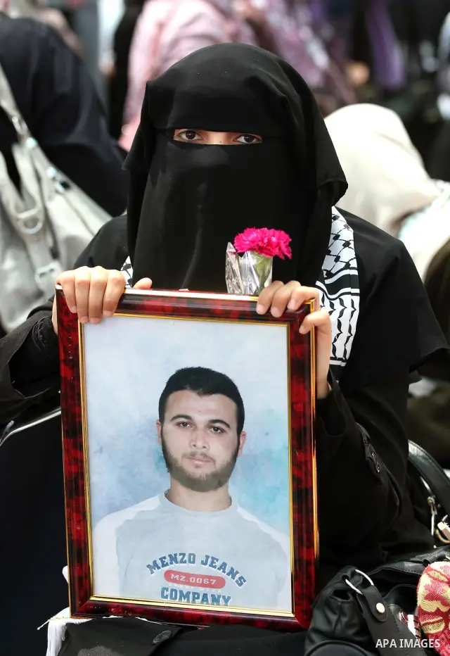 Palestinian woman holds up a portrait of prisoner outside the headquarters of the International Committee of the Red Cross (ICRC) during a protest in Gaza City, to show solidarity with Palestinian prisoners held in Israe...