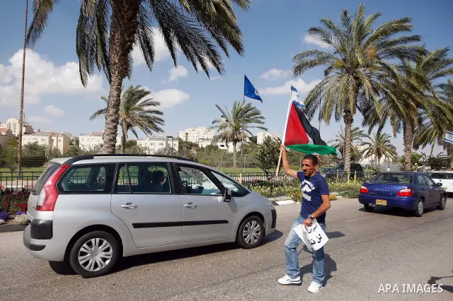 Dozens of Palestinian, Israeli and foreign activists hold Palestinian flags as they gather near the Maale Adumim settlement in West Bank on May 13, 2012 during a demonstration in support of Palestinian prisoners observin...