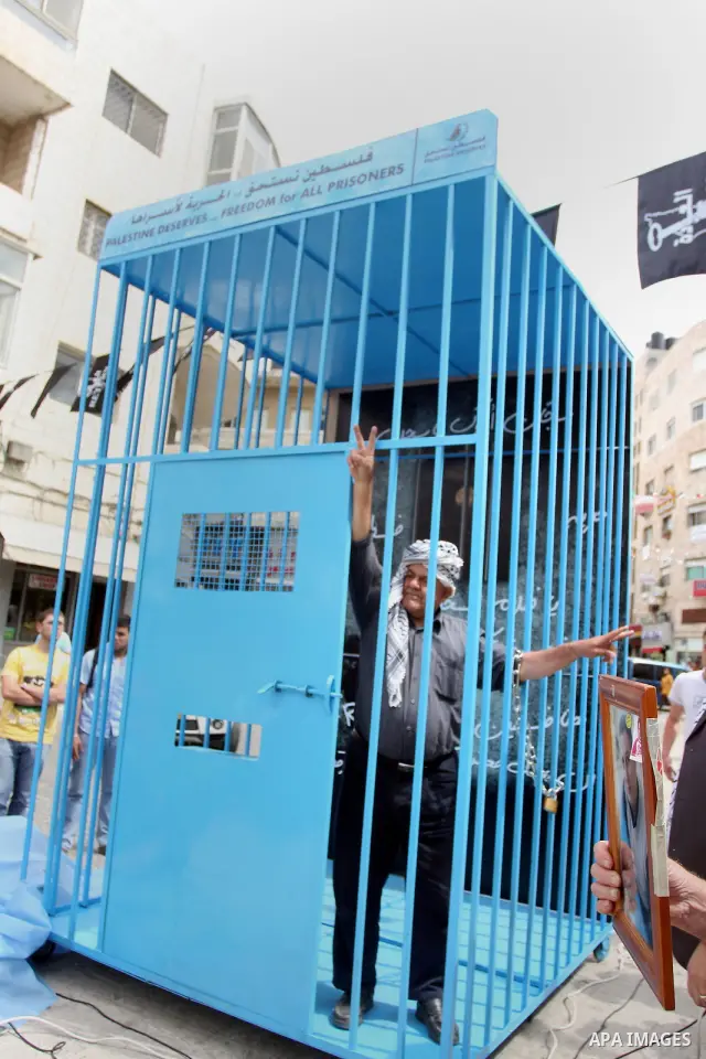 A Palestinian man gestures from inside a mock prison cell during a rally in the West Bank city of Ramallah, in support of Palestinian prisoners on a hunger strike in Israeli jails May 14, 2012. One in three of the 4,800...