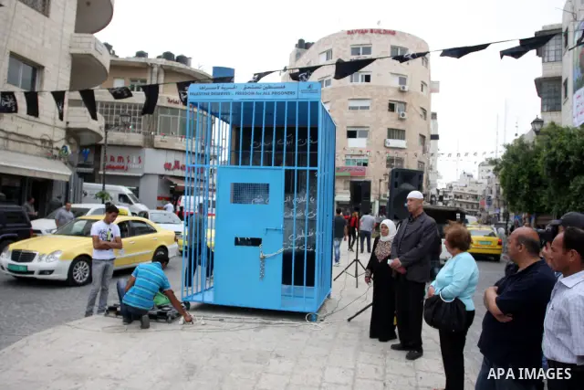 A Palestinian man gestures from inside a mock prison cell during a rally in the West Bank city of Ramallah, in support of Palestinian prisoners on a hunger strike in Israeli jails May 14, 2012. One in three of the 4,800...
