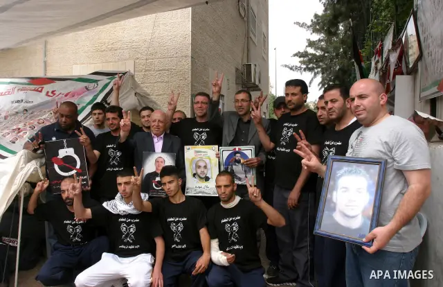 Palestinian protesters hold pictures of Palestinian prisoners during a visit to a protest tent outside the International Committee of the Red Cross (ICRC) offices in East Jerusalem, as the protestors join the hunger stri...