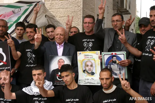 Palestinian chief negotiator Ahmed Qorei (C) holds a picture of a Palestinian prisoner and flashes the sign for victory during his visit to a protest tent outside the International Committee of the Red Cross (ICRC) offic...