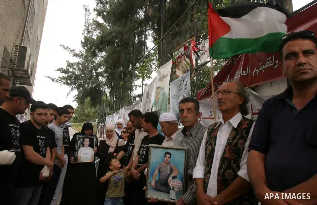 Palestinian protesters hold pictures of Palestinian prisoners during a visit to a protest tent outside the International Committee of the Red Cross (ICRC) offices in East Jerusalem, as the protestors join the hunger stri...