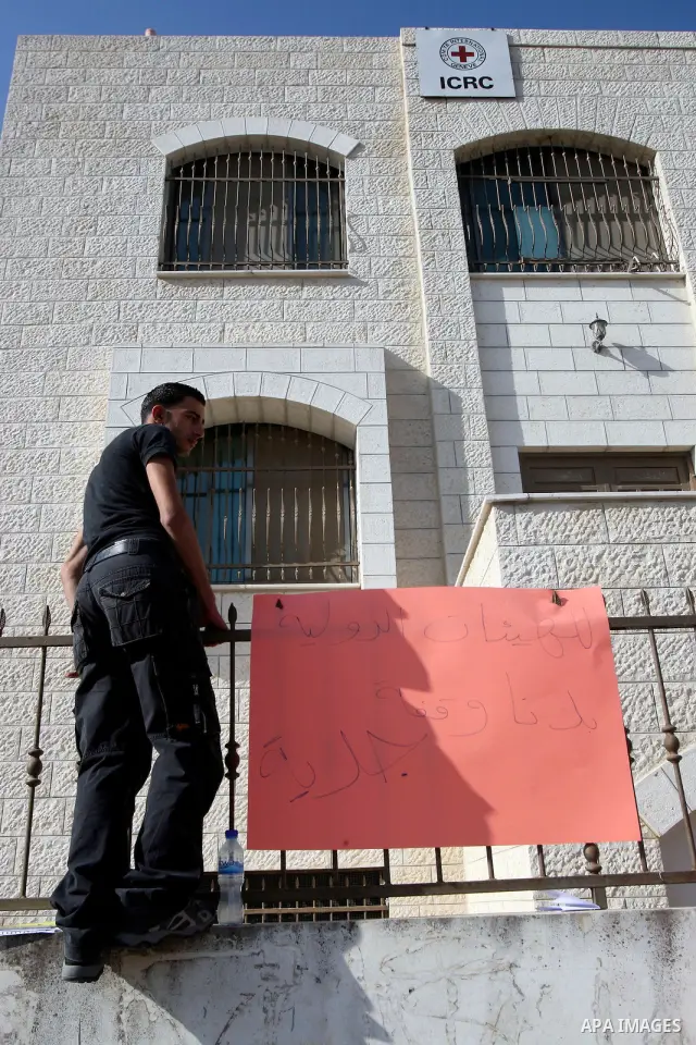 Palestinians attached a banners outside the headquarters of the International Committee of the Red Cross (ICRC) in the West Bank City of Nablus, 14 May 2012, as they forced the offices to close for three hours in solidar...