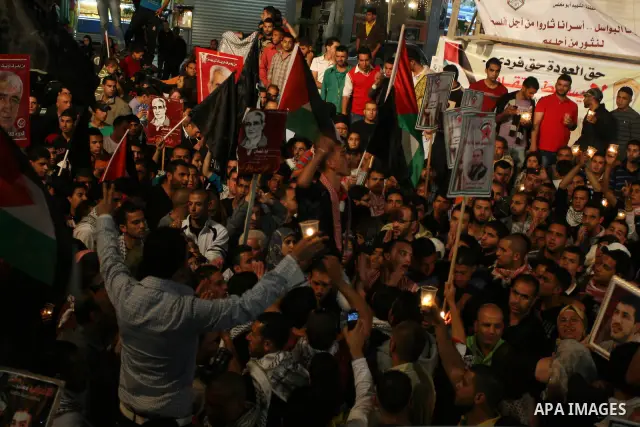 Palestinians hold pictures of prisoners and Palestinian flags as they celebrate the end of a prisoners' hunger strike in Israeli jails, in the West Bank city of Ramallah, Monday, May 14, 2012. Hundreds of Palestinian pri...