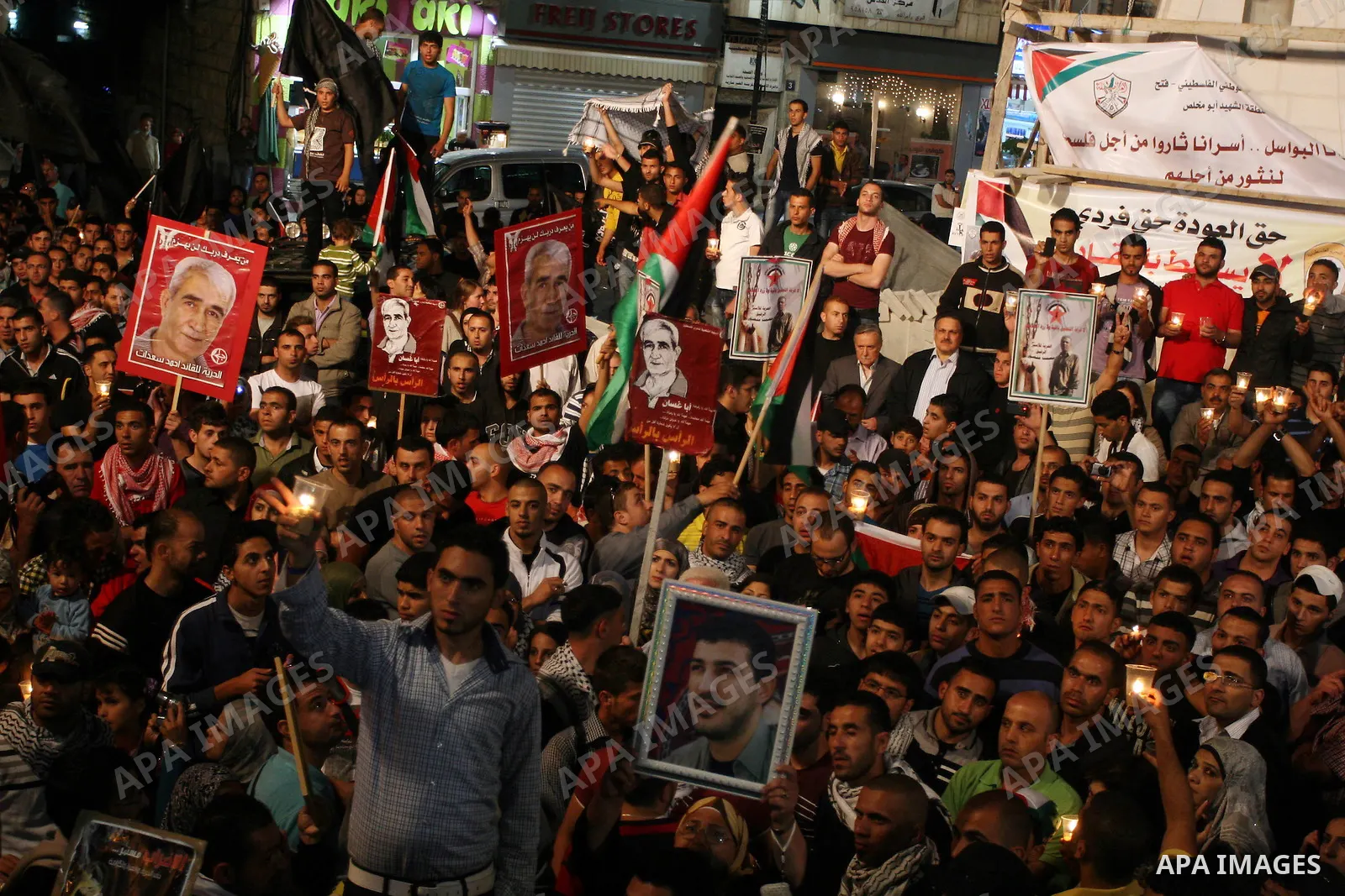 Palestinians hold pictures of prisoners and Palestinian flags as they celebrate the end of a prisoners' hunger strike in Israeli jails, in the West Bank city of Ramallah, Monday, May 14, 2012. Hundreds of Palestinian pri...