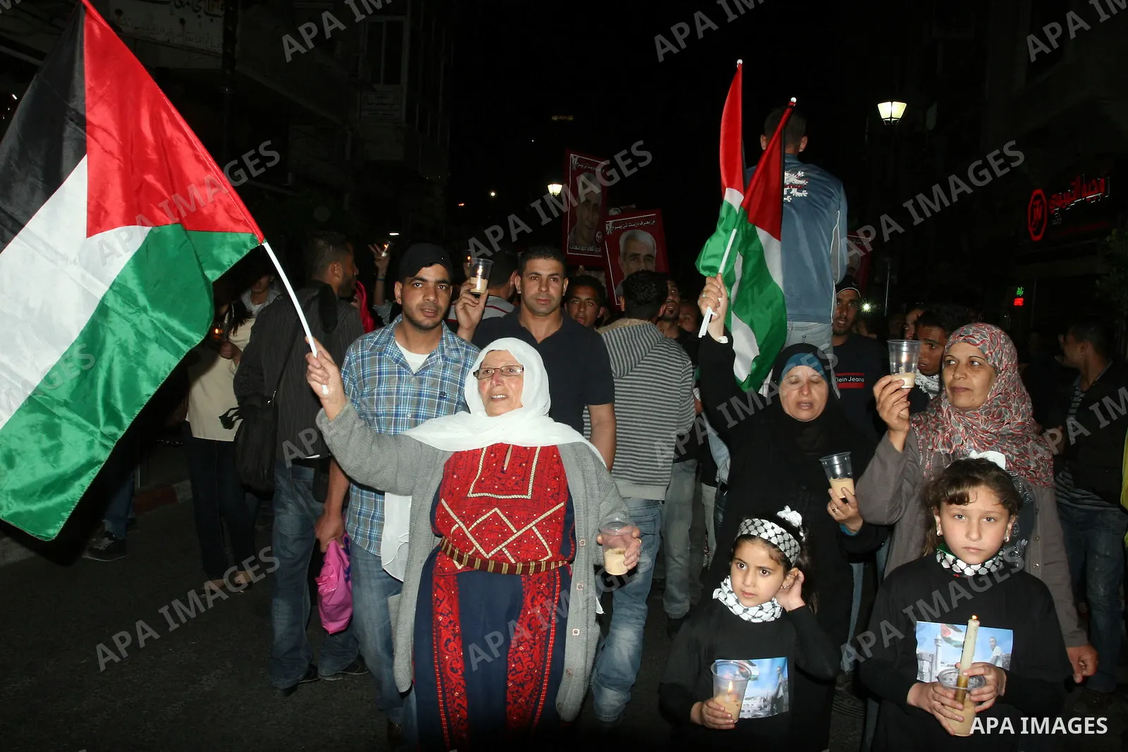 Palestinians hold pictures of prisoners and Palestinian flags as they celebrate the end of a prisoners' hunger strike in Israeli jails, in the West Bank city of Ramallah, Monday, May 14, 2012. Hundreds of Palestinian pri...