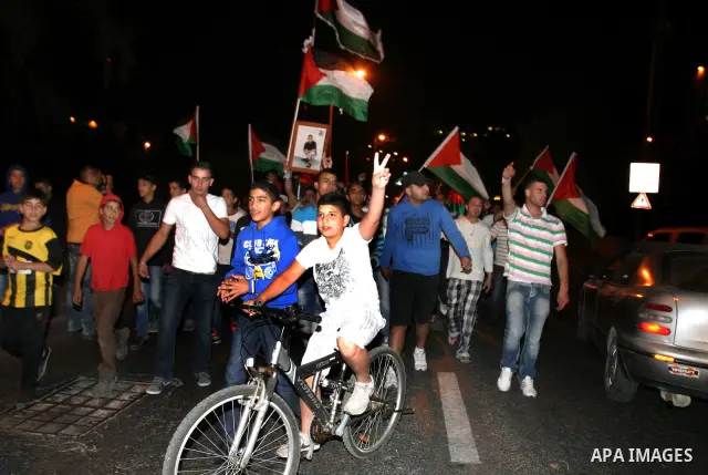 Palestinian hold national flags during celebrate after the signing of a deal to end the prisoners hunger strike in Jerusalem on 14 May 2012. Israel and Palestinian signed an agreement 14 May ending a mass hunger strike b...