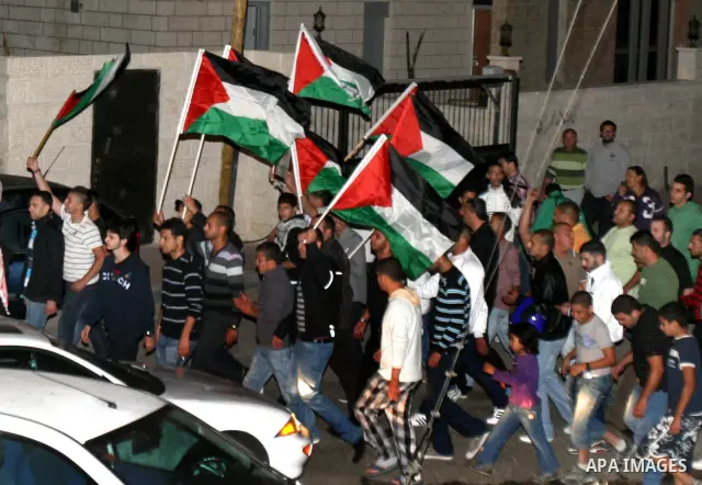 Palestinian hold national flags during celebrate after the signing of a deal to end the prisoners hunger strike in Jerusalem on 14 May 2012. Israel and Palestinian signed an agreement 14 May ending a mass hunger strike b...